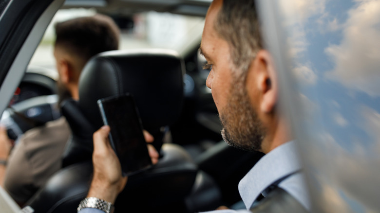 man on phone in car sitting behind driver