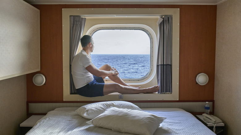 Man sitting in cruise ship window looking out at the ocean