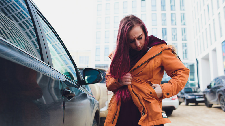Woman in orange jacket looking for something in her pocket