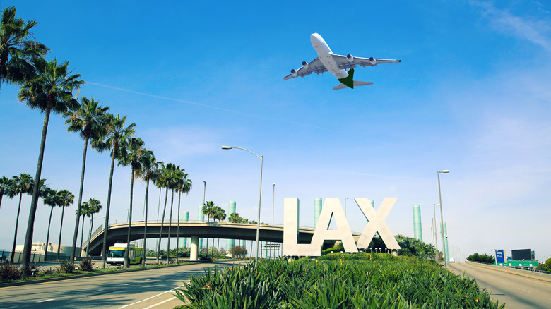 A plane taking off over the LAX sign at Los Angeles International Airport