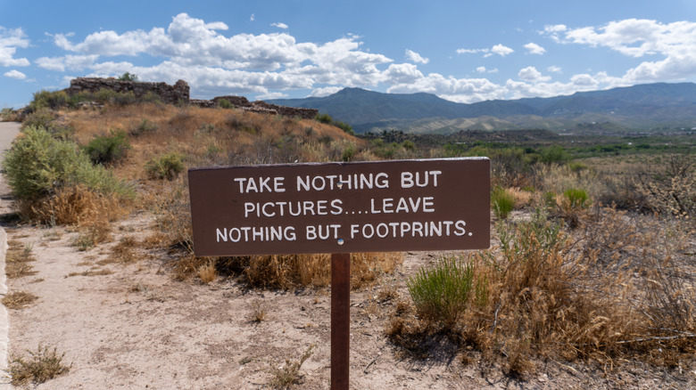 Sign that says "take nothing but pictures ... leave nothing but footprints" in wilderness