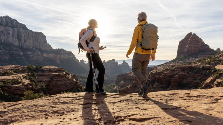 Older couple stands on desert trail overlooking red rocks