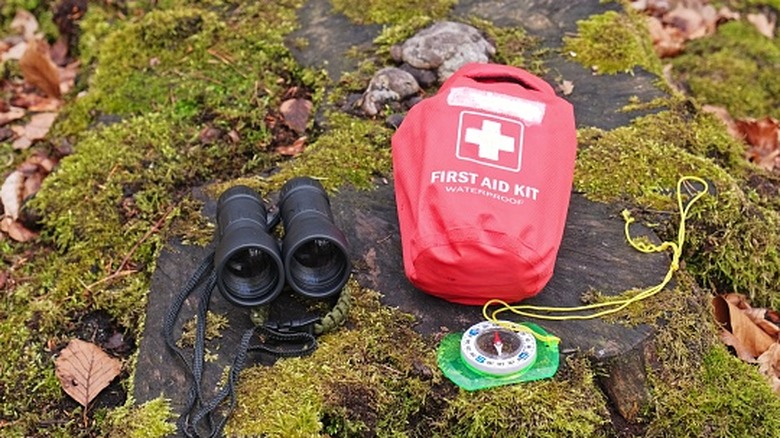 Hiking first aid kit and binoculars on moss