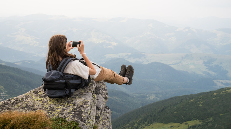 Hiker sits on edge of cliff to take photo