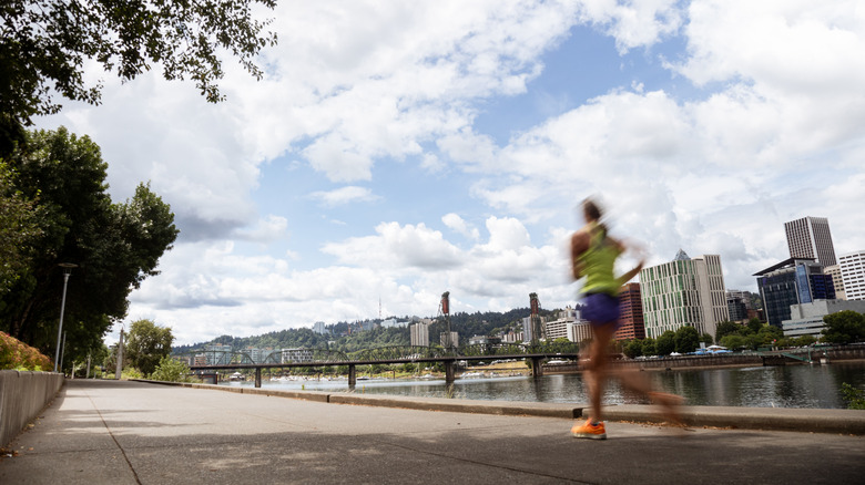 a woman in motion, blurred runs along the columbia river waterfront trail in portland, oregon