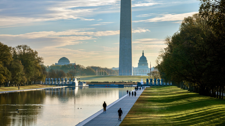 figures walking along the national mall with the washington monument and capitol building in the distance; washington d.c.