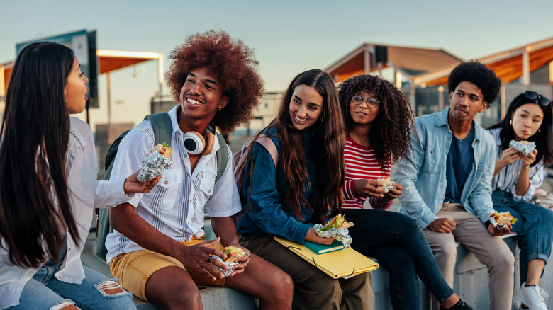 A group of diverse friends eating outdoors