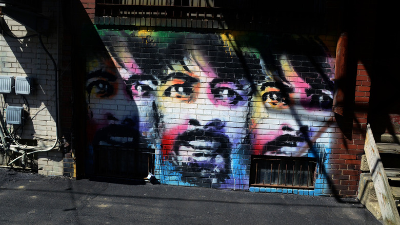 Mural in Dave Grohl Alley, with 3 colorful portraits of Dave Grohl on a brick wall