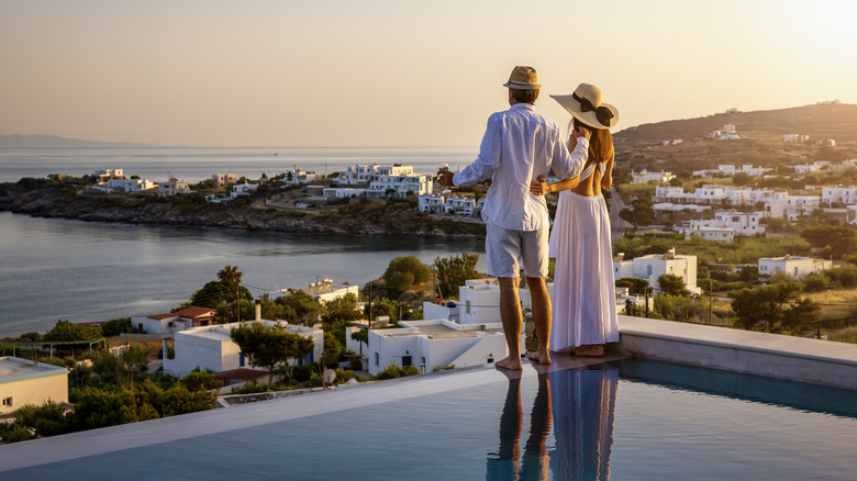 Couple standing by a pool looking over the Aegean Sea