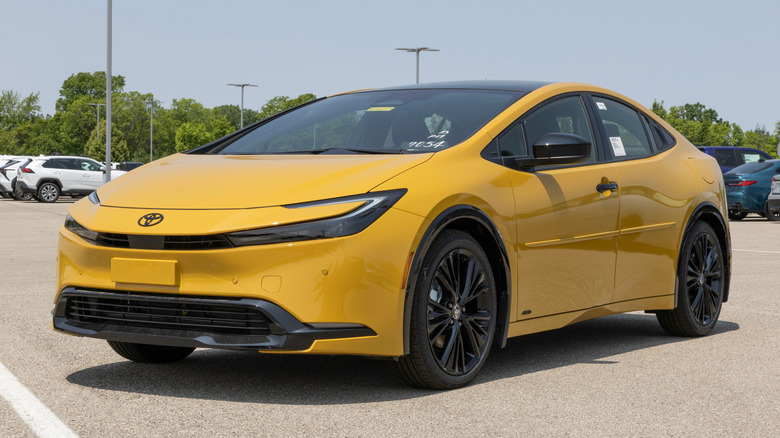 A yellow Toyota Prius parked in the lot of a dealership