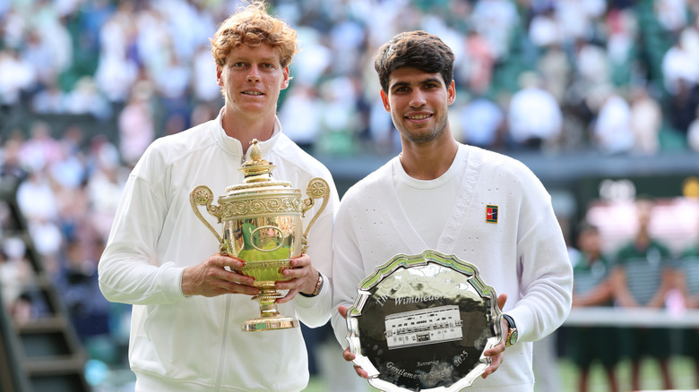 Jannik Sinner and Carlos Alcaraz pose with trophies at Wimbledon.
