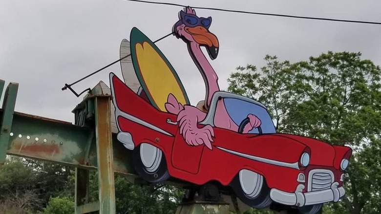Oil pump decorated with a flamingo driving a convertible with a surfboard inside in Luling