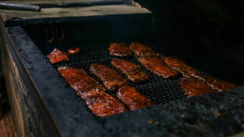 Slabs of smoked and grilled ribs in a row inside a bbq pit in Luling