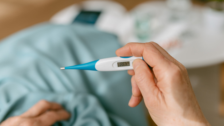 Over-the-shoulder view of a person holding a digital thermometer