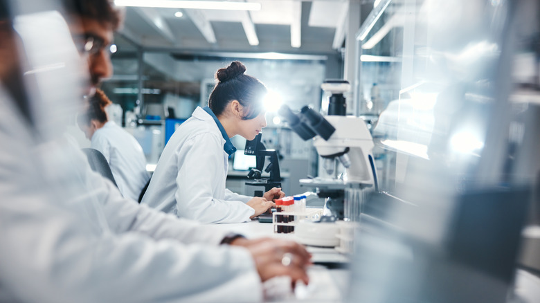 Medical, research and scientist in laboratory with microscope, observation and experiment for study