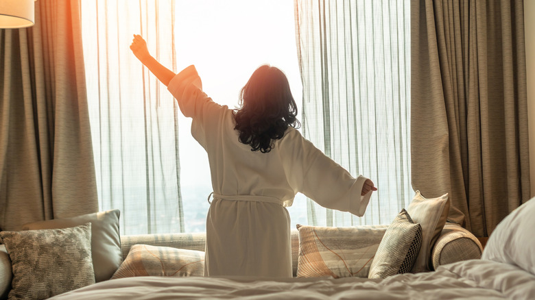 Woman waking up from good sleep on hotel bed and stretching
