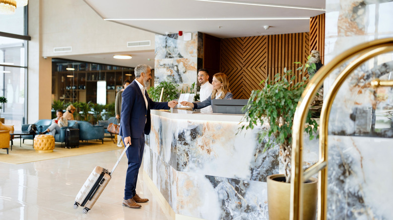 Elegantly dressed businessman talking with a receptionist while checking out from the hotel