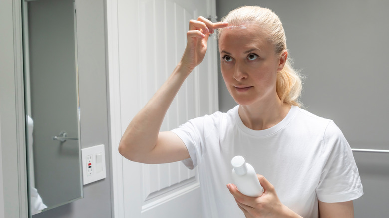 woman putting sunscreen on scalp