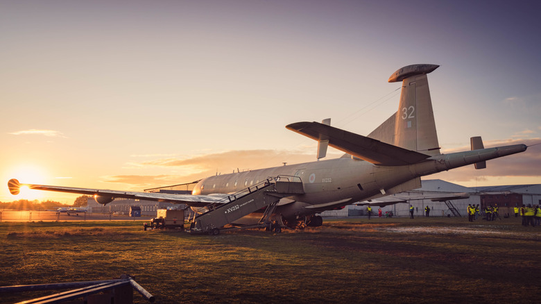 The sun sets as people work around a Hawker Siddeley Nimrod MR.2 plane at Coventry Airport.