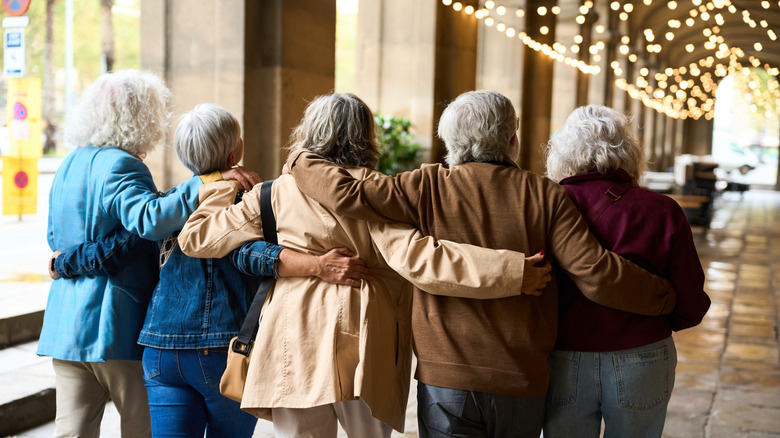 Group of seniors walking arm in arm under British style colonnade