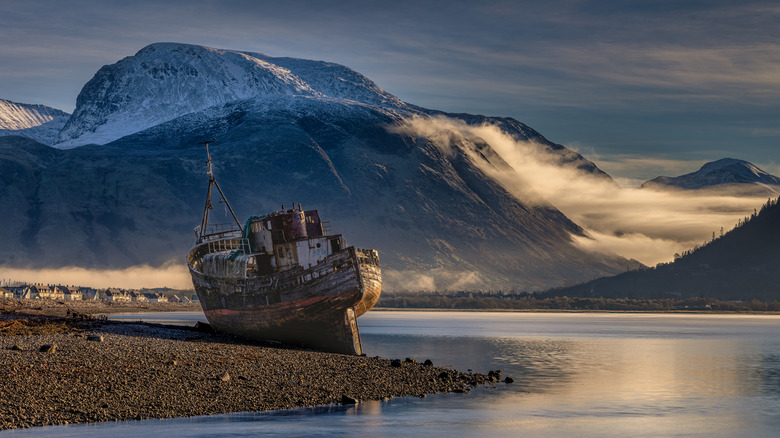 An abandoned fishing boat rests on the shore of Loch Levin, at the foot of Ben Nevis