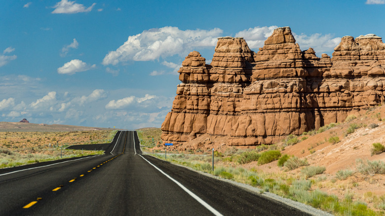 Blacktop highway next to red rock formations