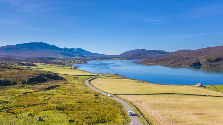Motorhomes driving along side a mountain loch in Scotland