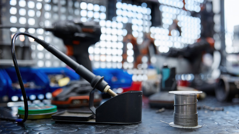 Soldering iron on a work bench, surrounded by other tools in the background.