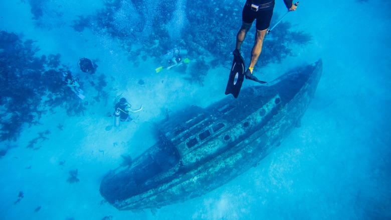 Snorkelers exploring a shipwreck in the water by San Andres