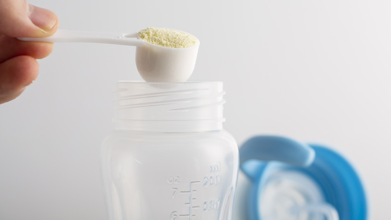 Person scooping baby formula into bottle