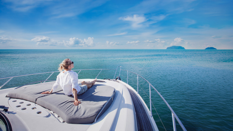 A woman sits on the bow of a luxury yacht, gazing out to sea