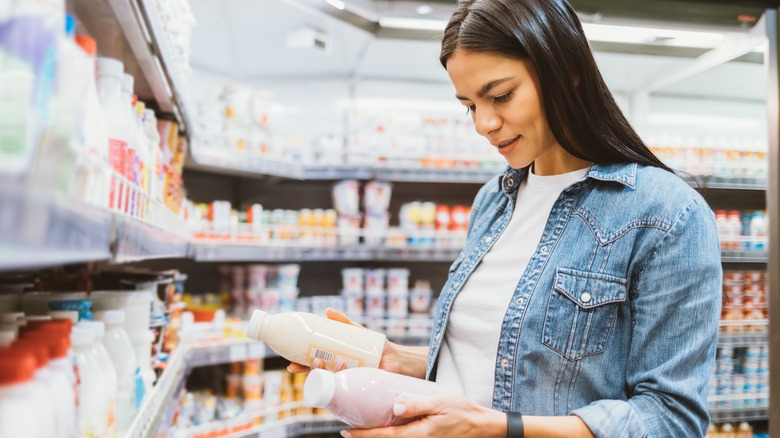Woman reads nutrition label of yogurts at store