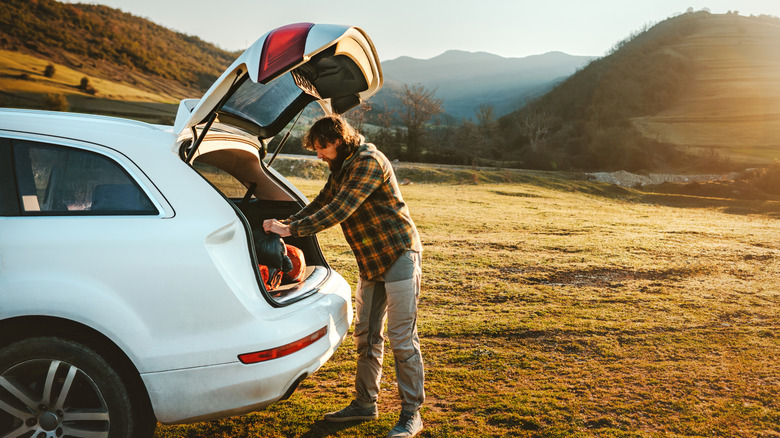 Person putting luggage in the trunk of a rental car