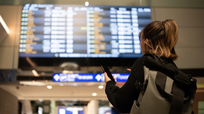 Traveler checking departure screen in airport terminal