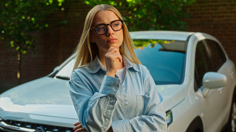 Pensive traveler standing in front of a car