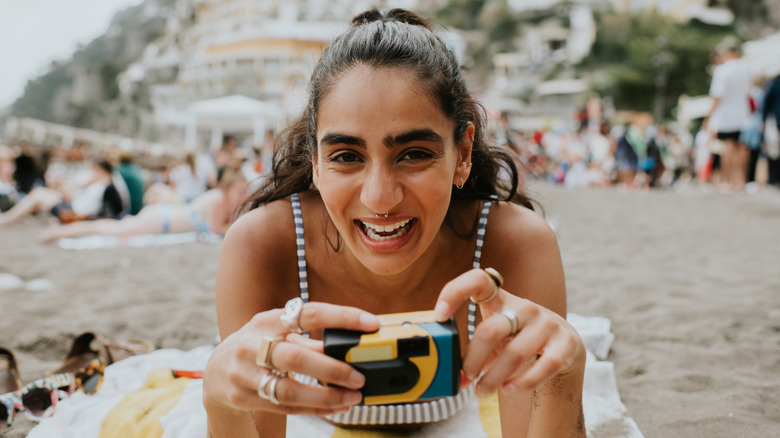 A woman on a beach with a disposable camera