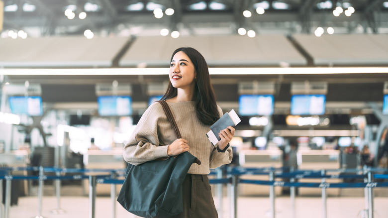 A woman holds a boarding pass at an airport