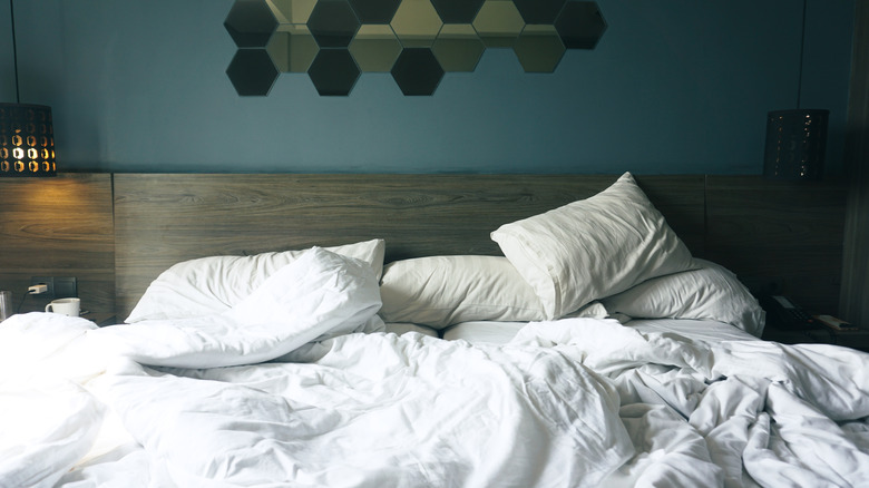 Crumpled bed sheets and comforter in a hotel room.