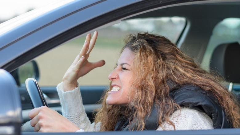 A frustrated woman gesturing in a car driver's seat