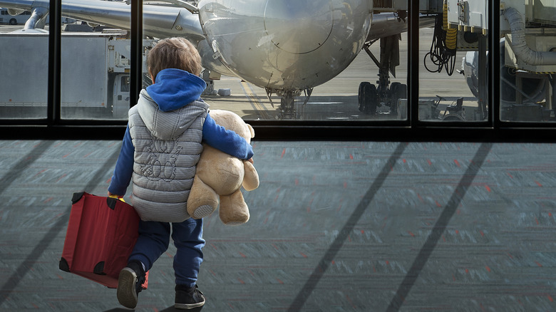 Child with suitcase and stuffed animal at the airport
