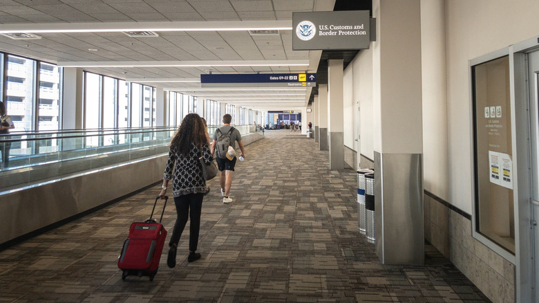 People walking past U.S. Customs and Border Protection sign at airport