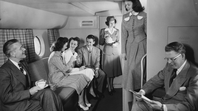 An air stewardess pours a hot drink as passengers relax in the lounge of a Pan American Airways Boeing 377 Stratocruiser