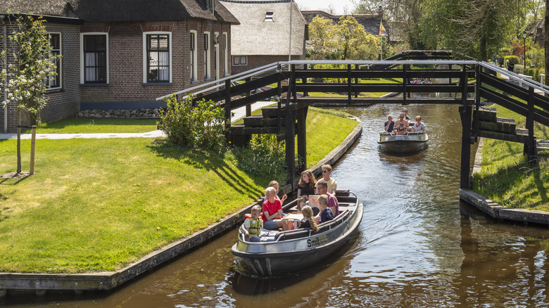 Small boats sailing the canals of Giethoorn with a wooden bridge and cottages