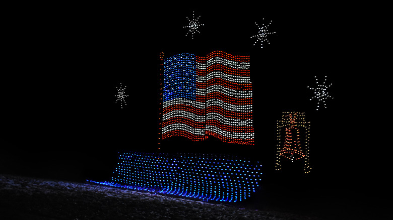 An American flag, the Liberty Bell, and various snowflakes are shaped out of light bulbs during a nocturnal winter scene in Oglebay, West Virginia