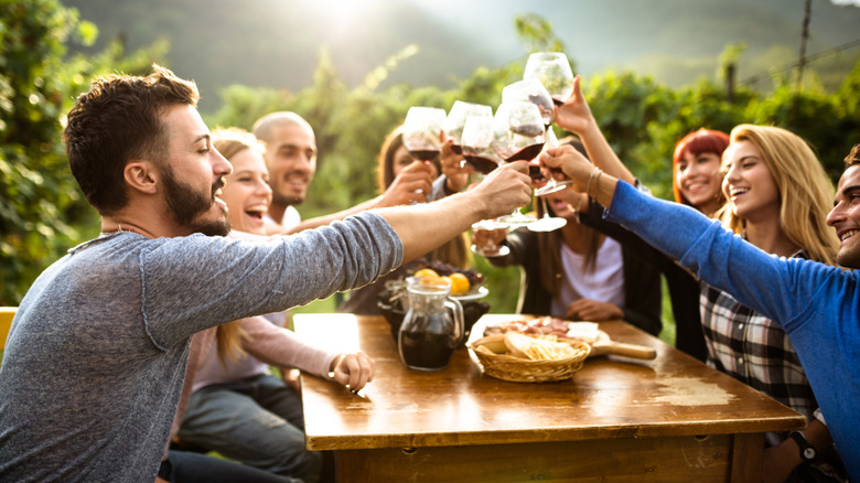 People clinking glasses happily at a wine tasting with food