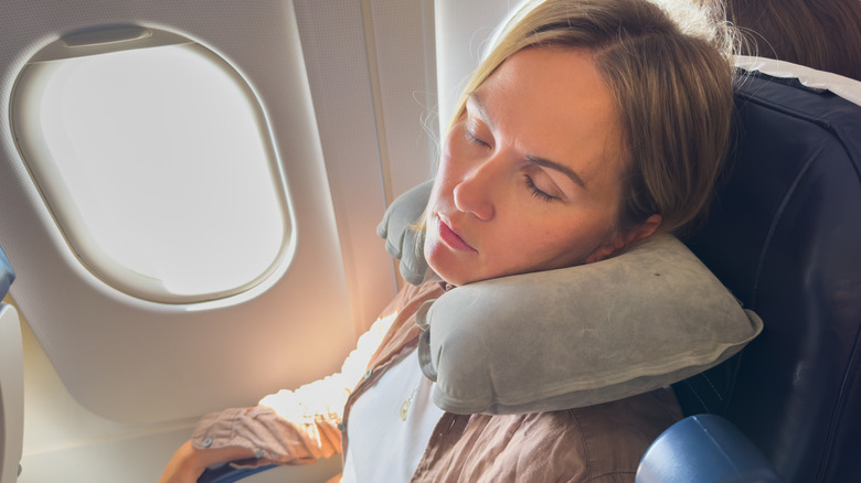 Woman sleeping on plane wearing a neck pillow
