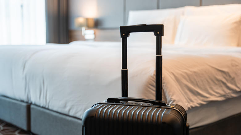 Hotel bed with suitcase in foreground