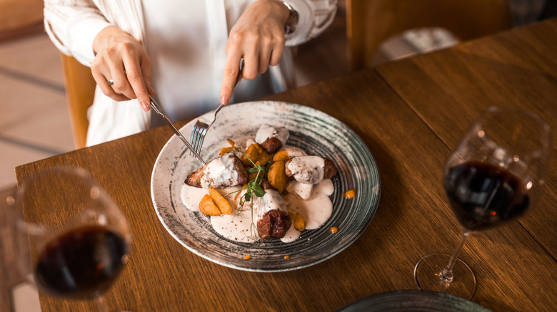 Someone holding cutlery at dinner