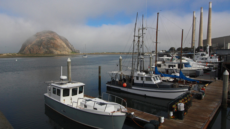 Misty Morro Rock in the bay with boats in the foreground and the three stacks in the background