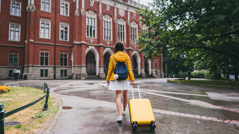 A girl with a yellow suitcase is arriving to stay at a historic residence hall in Krakow